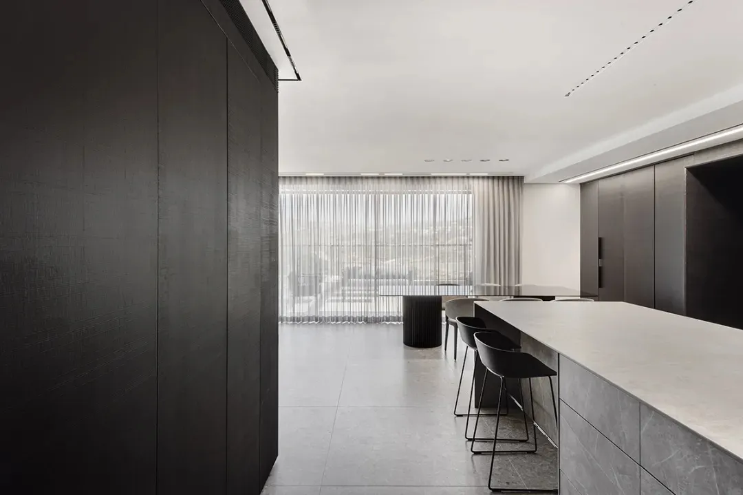 A modern minimalist kitchen with concrete countertops and dark cabinetry.