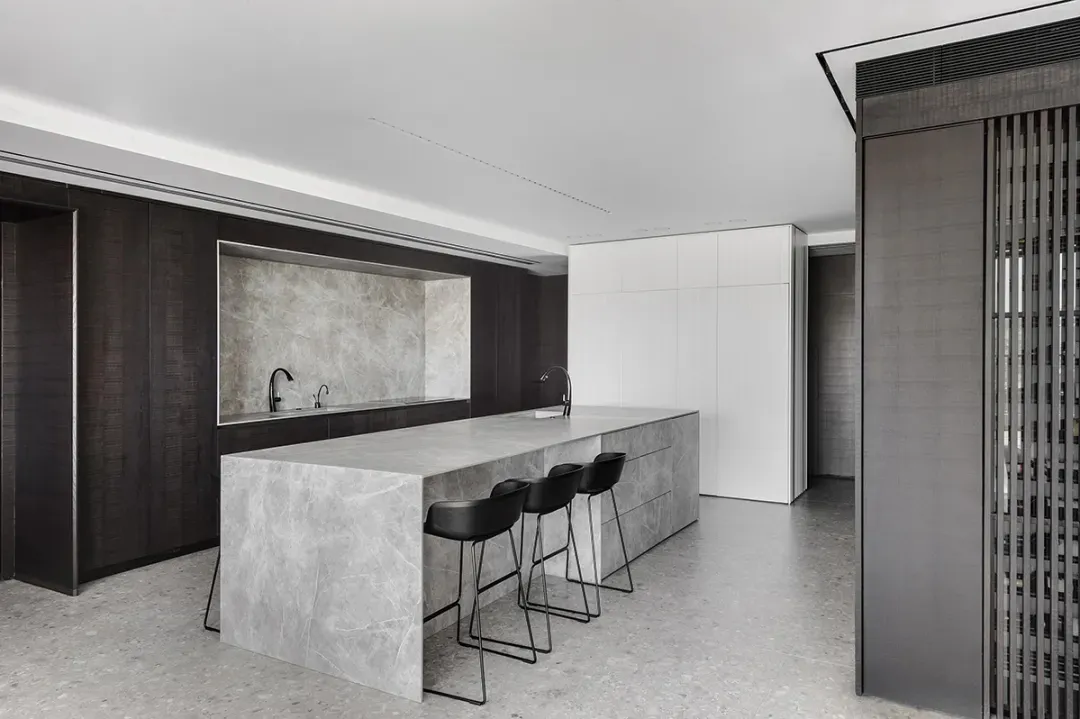 A modern kitchen with a marble island and concrete flooring.
