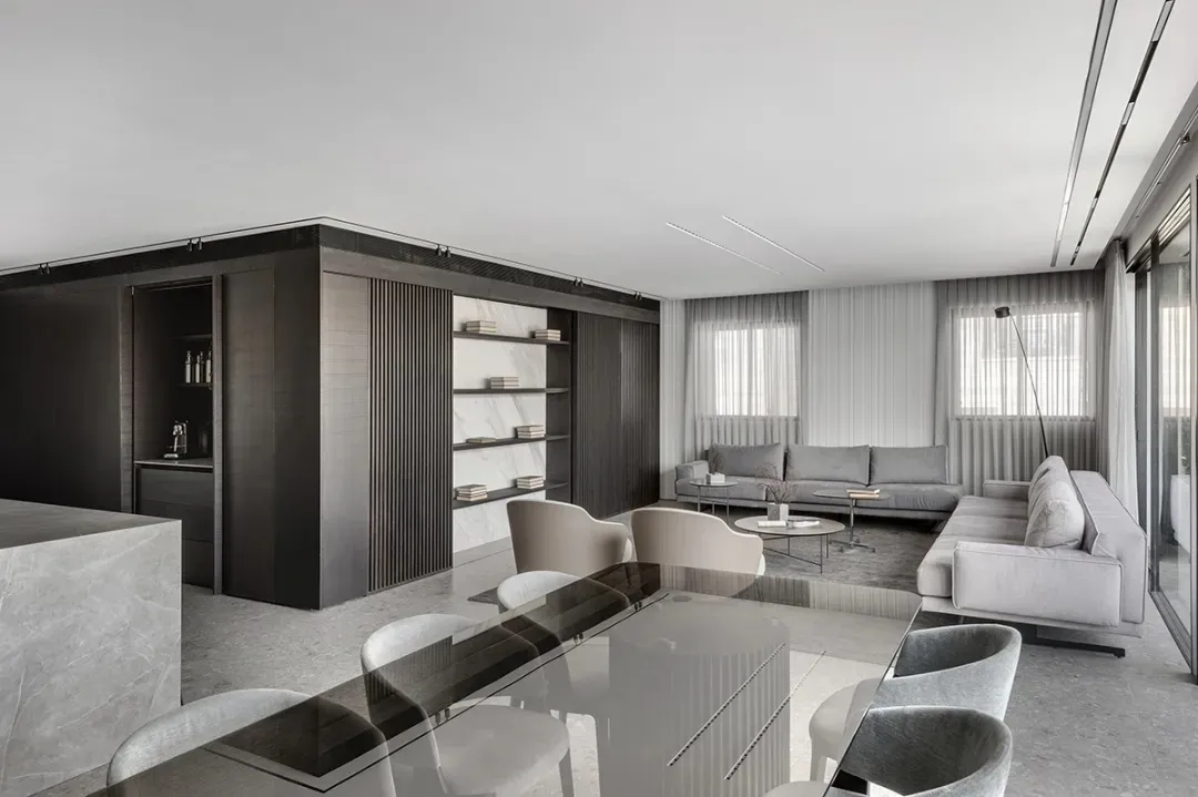 A modern living room with minimalist furniture, cement flooring, wooden panels, and marble accents.