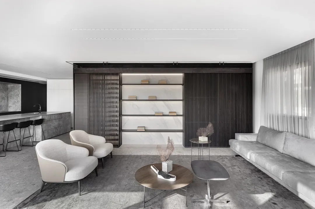 Modern, minimalist living room with marble accents, wooden slat wall, and concrete floor.