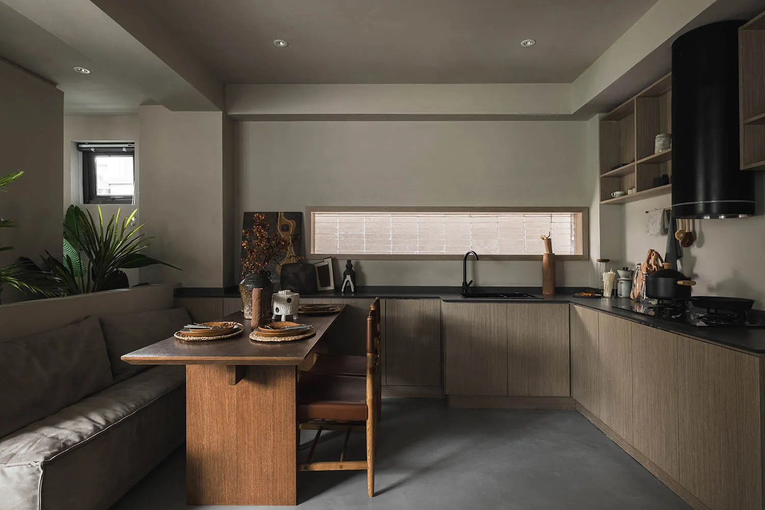 A modern minimalist kitchen with dark wood cabinetry and a long table.