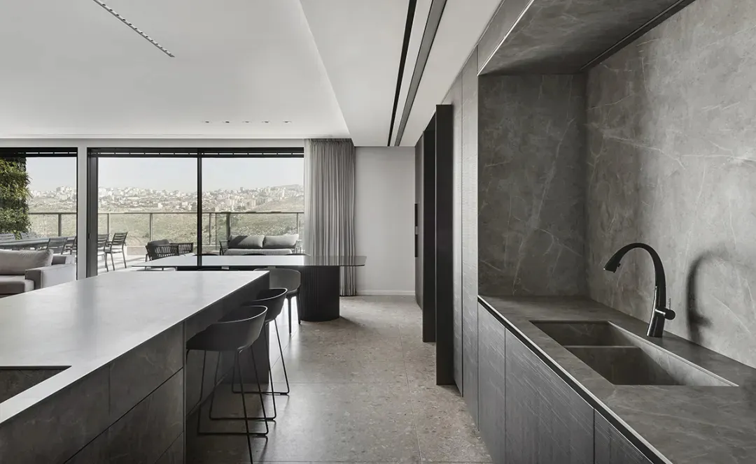 A modern residential kitchen with a marble island and concrete flooring.