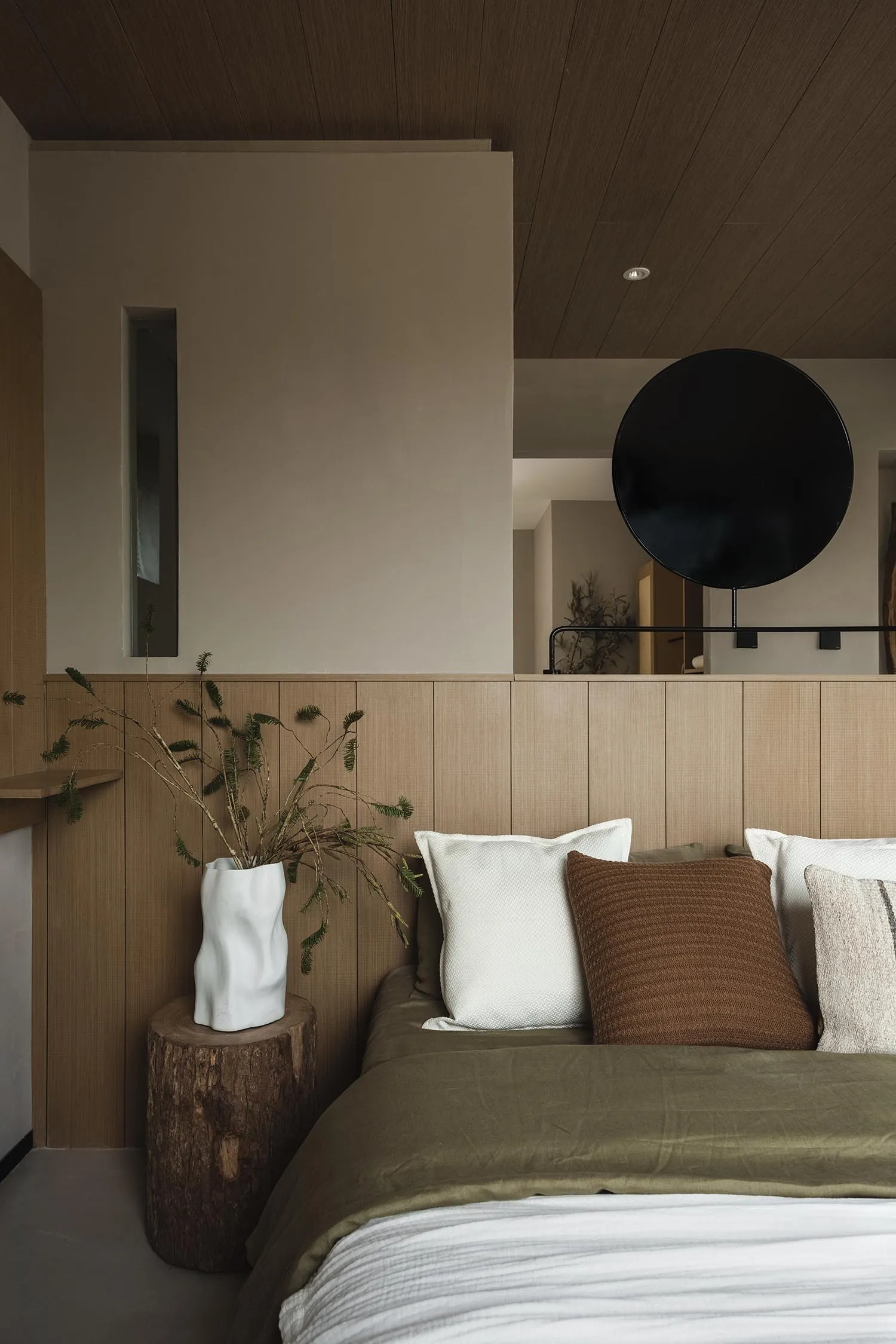 A minimalistic bedroom featuring a wooden headboard wall and soft lighting.