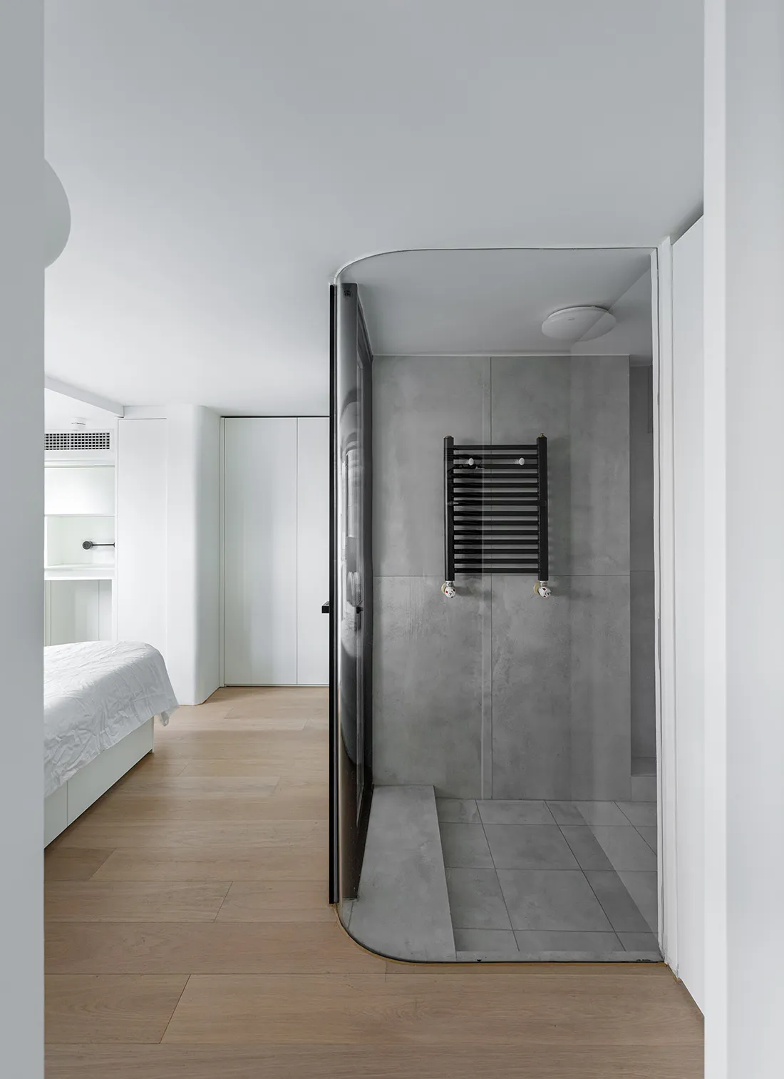 Modern minimalist bathroom with concrete walls and floor, featuring a black towel warmer on the wall.