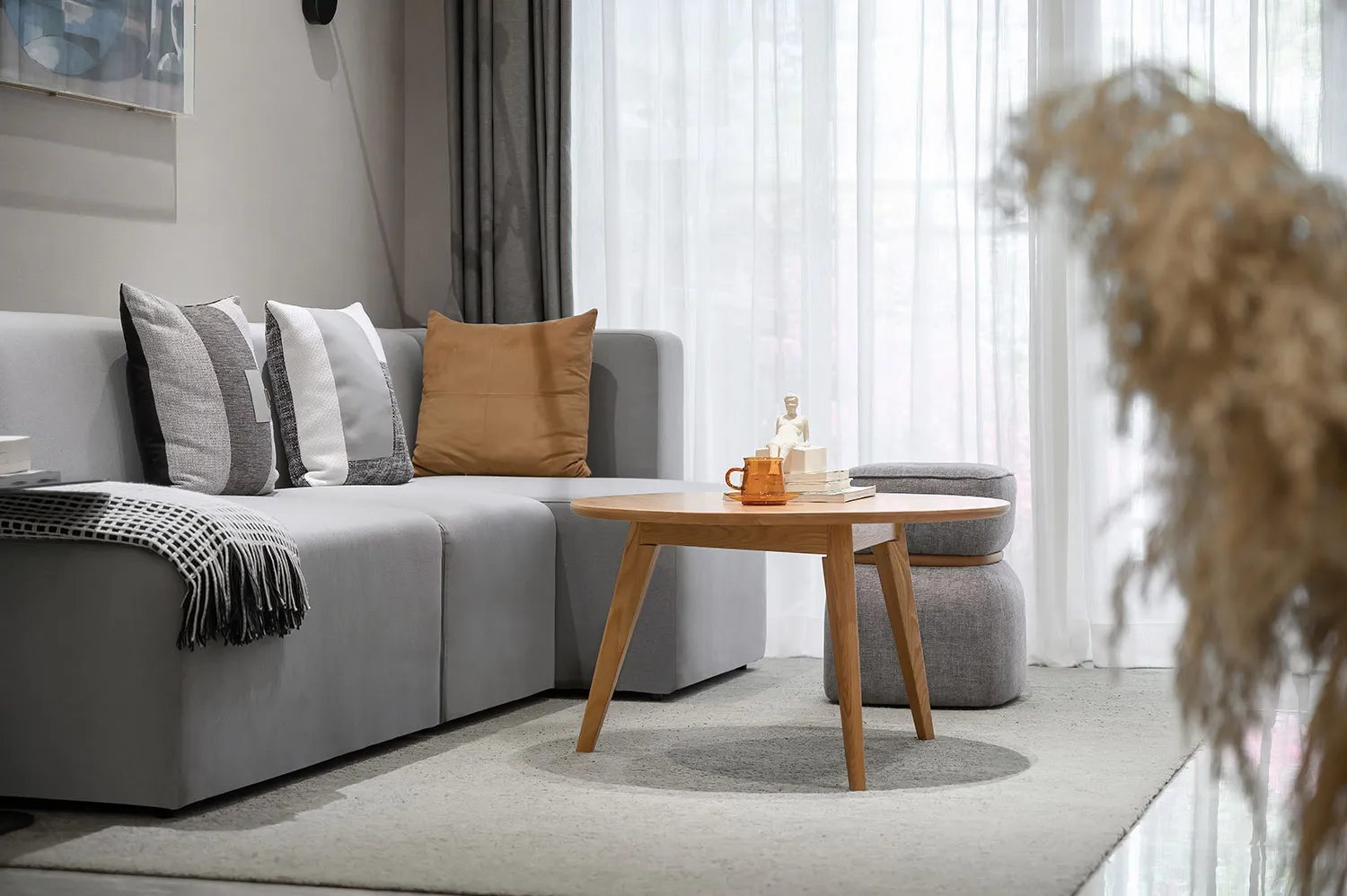 Modern minimalist living room featuring a gray sectional couch adorned with multiple pillows and a throw blanket, accompanied