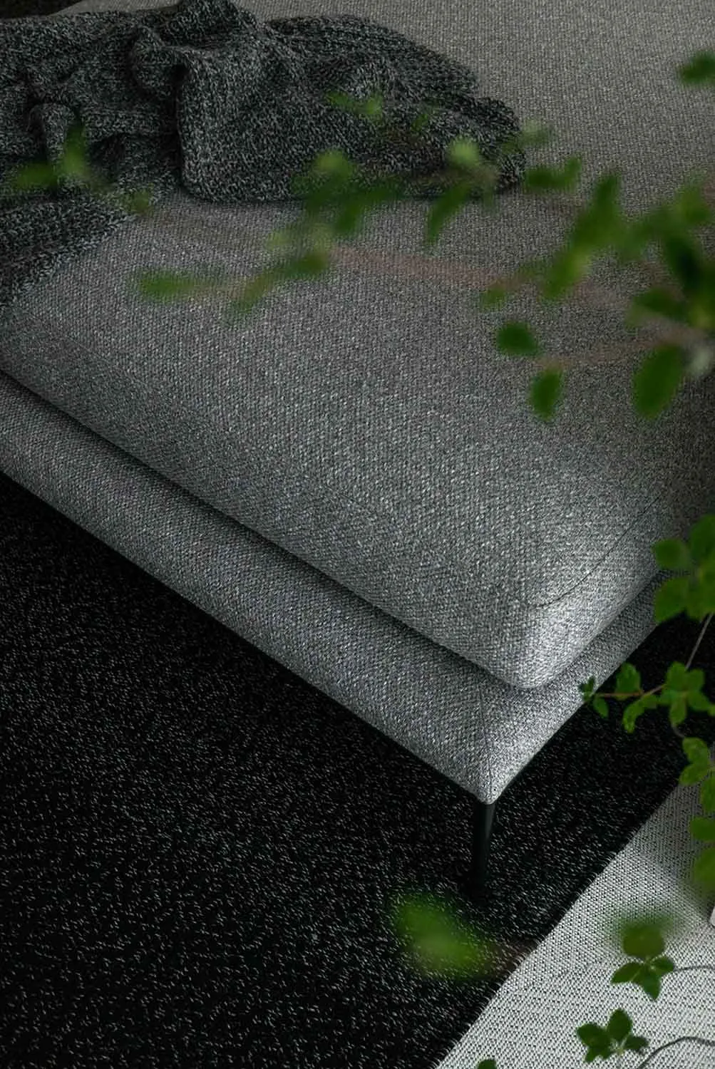 Modern living room featuring a grey sofa with fabric upholstery and black legs.
