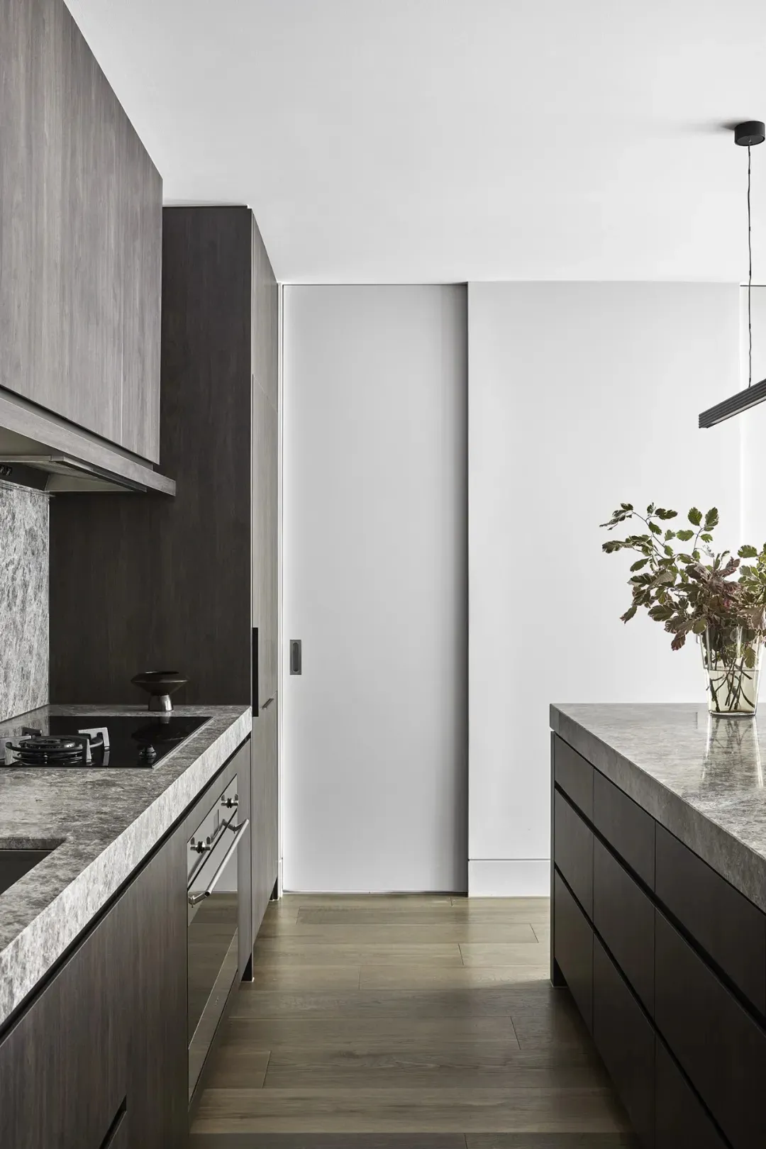 Modern minimalist kitchen with concrete countertops and wooden flooring.