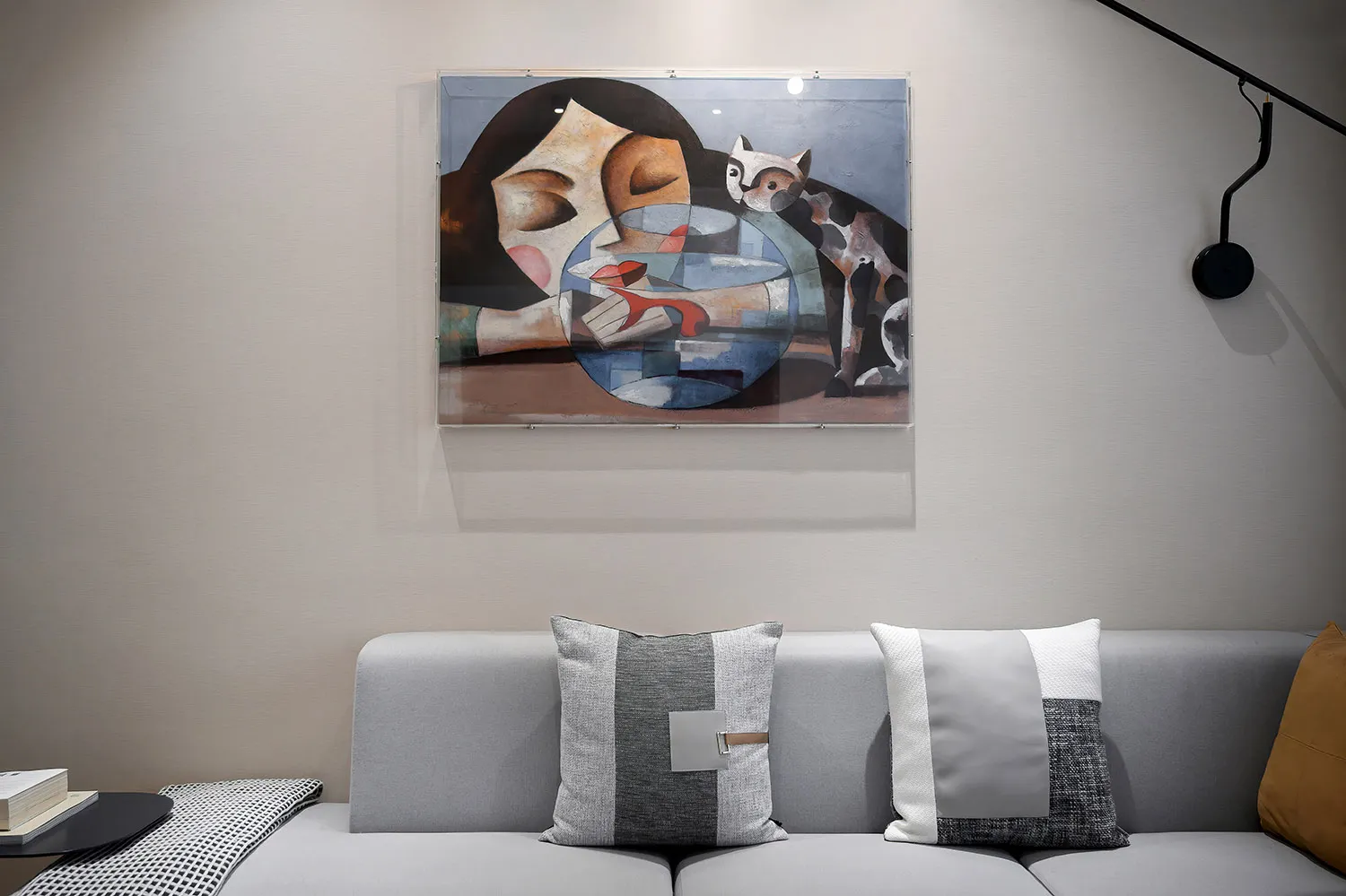 A modern living room featuring a contemporary abstract painting hung above a gray sofa with patterned pillows and a small tab