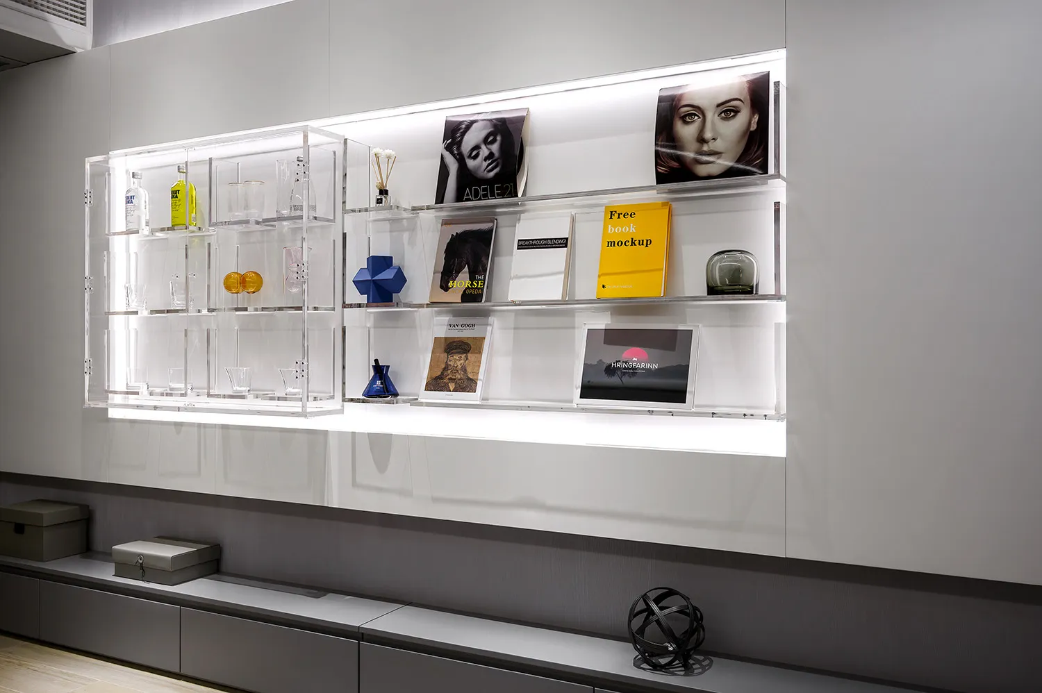 Modern minimalist shelf display featuring clear glass shelving with books, glassware, and decorative items.