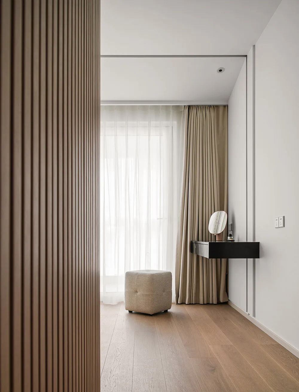 Modern bedroom featuring wooden flooring, a hanging desk with a round mirror, and curtains.