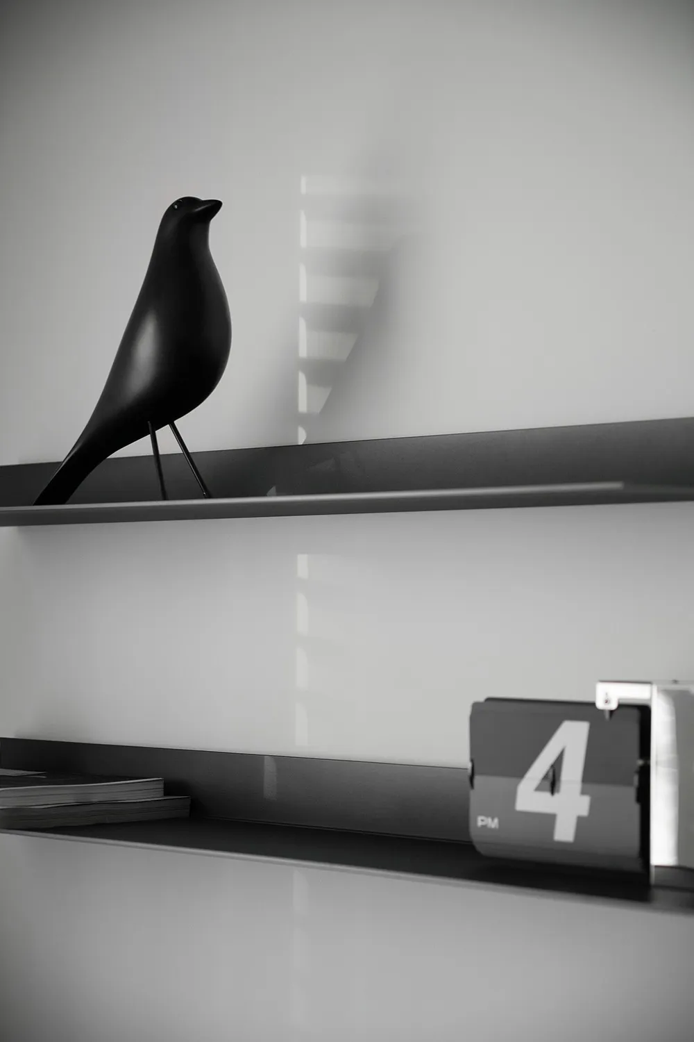 A minimalist black bird figurine perched on a sleek black shelf.