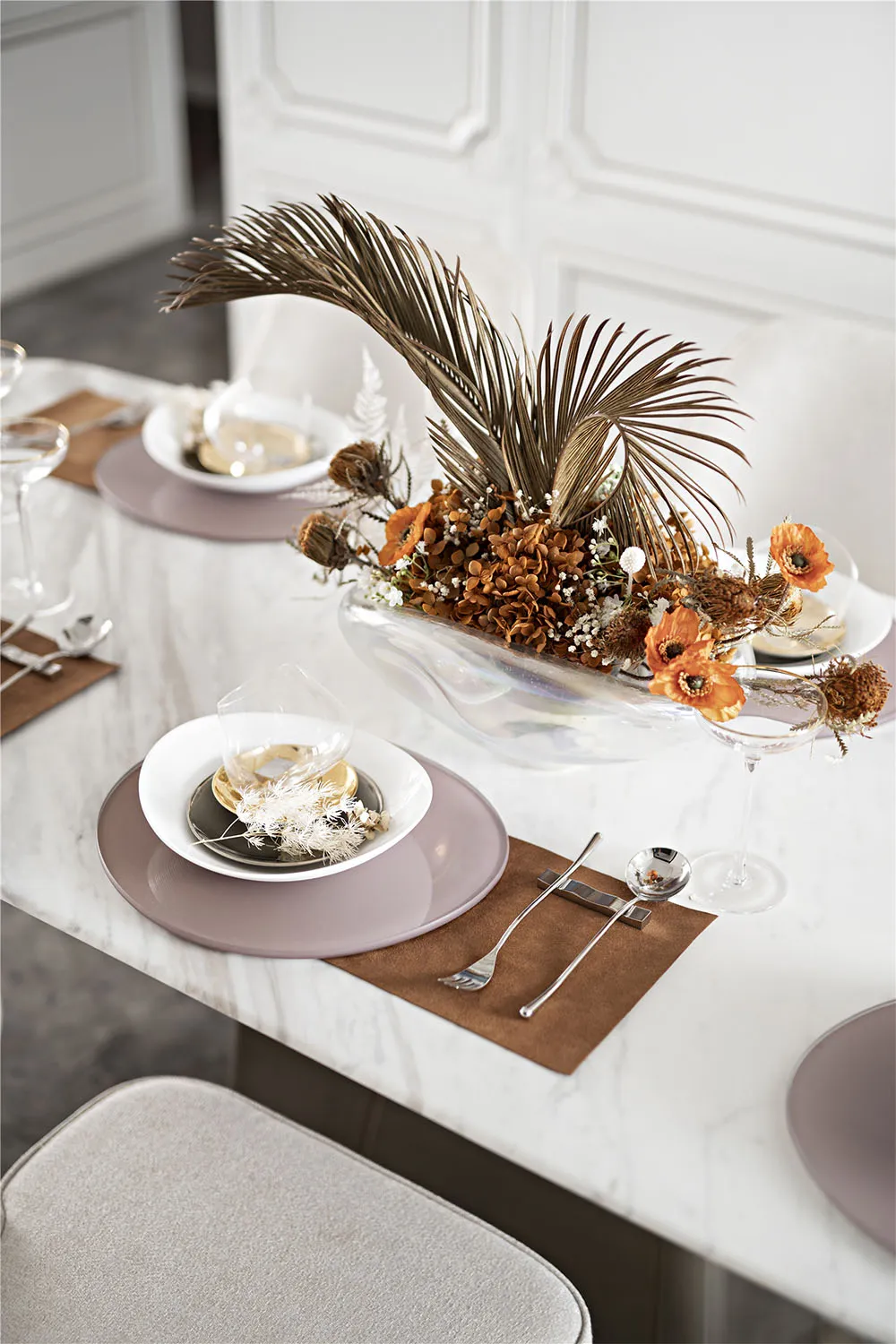 Modern dining room with a glass centerpiece featuring dried flowers and foliage.