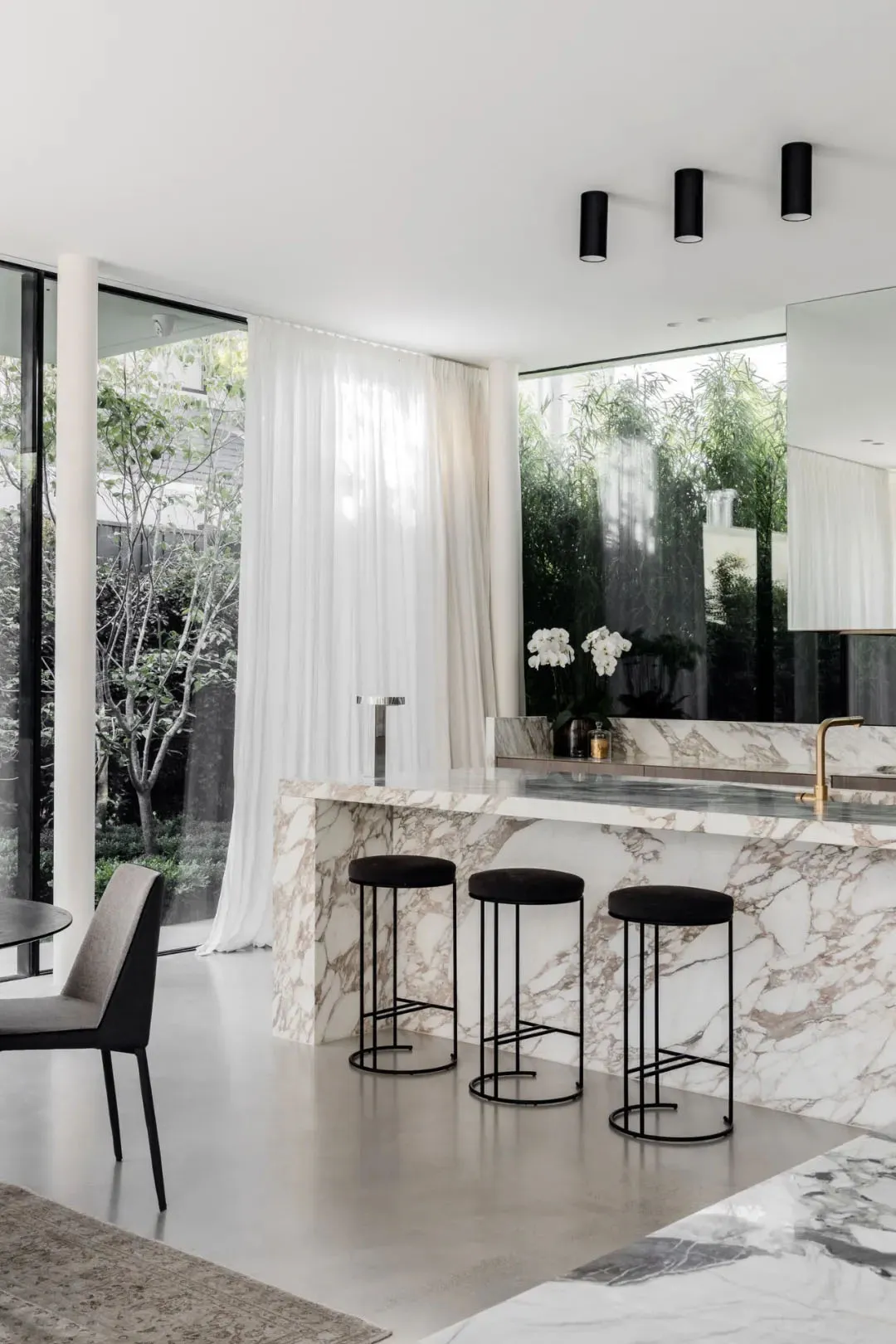A modern interior space featuring a marble countertop and stools with a minimalist decor.