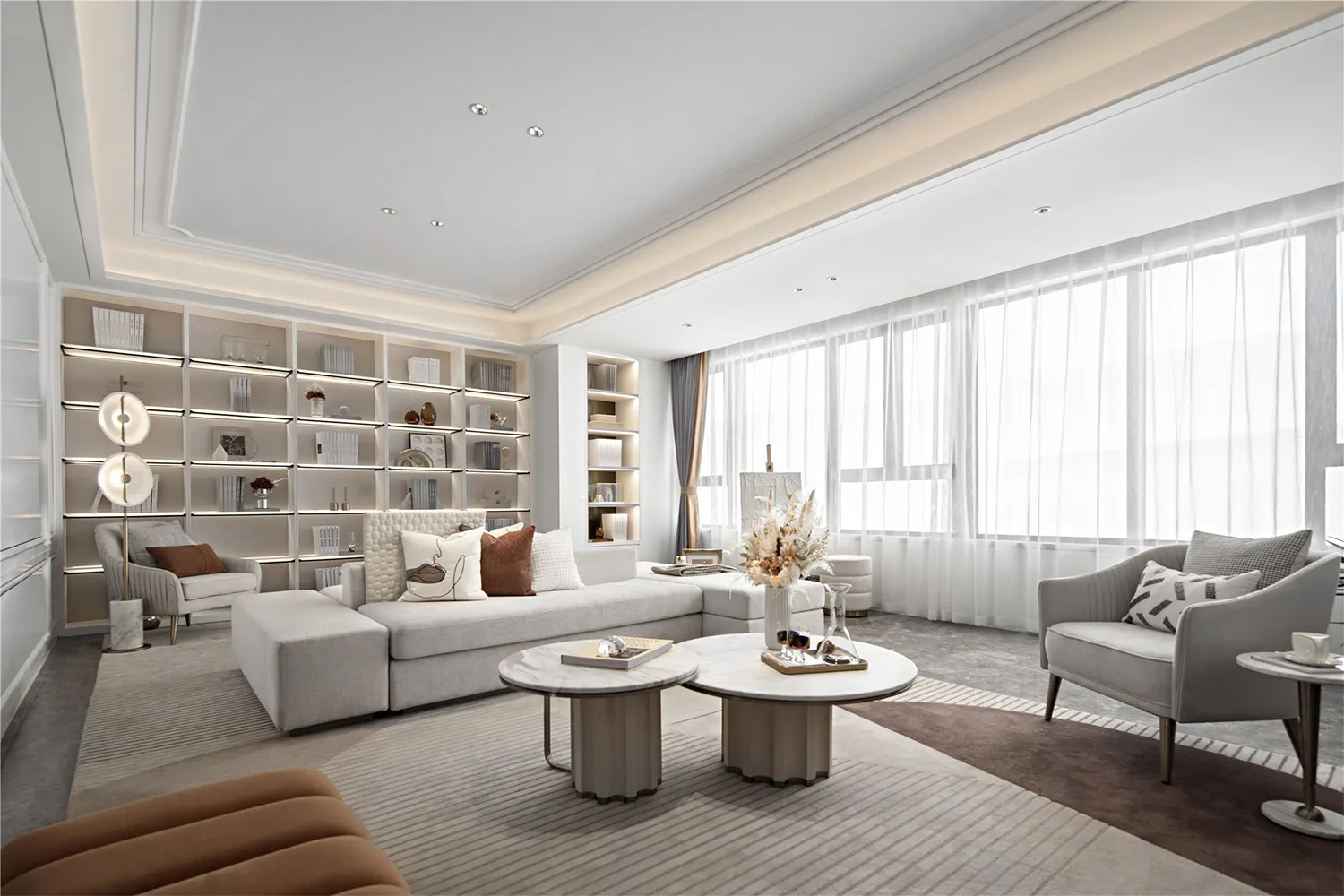 Modern living room with fabric seating, glass coffee tables, and metallic accents.
