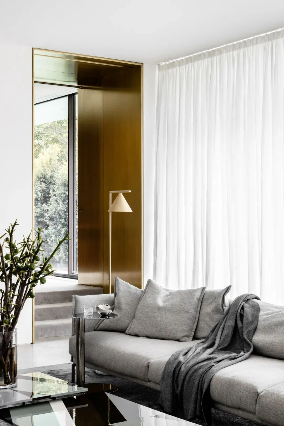 Modern living room with a gray sofa, white curtains, and a brass floor lamp.