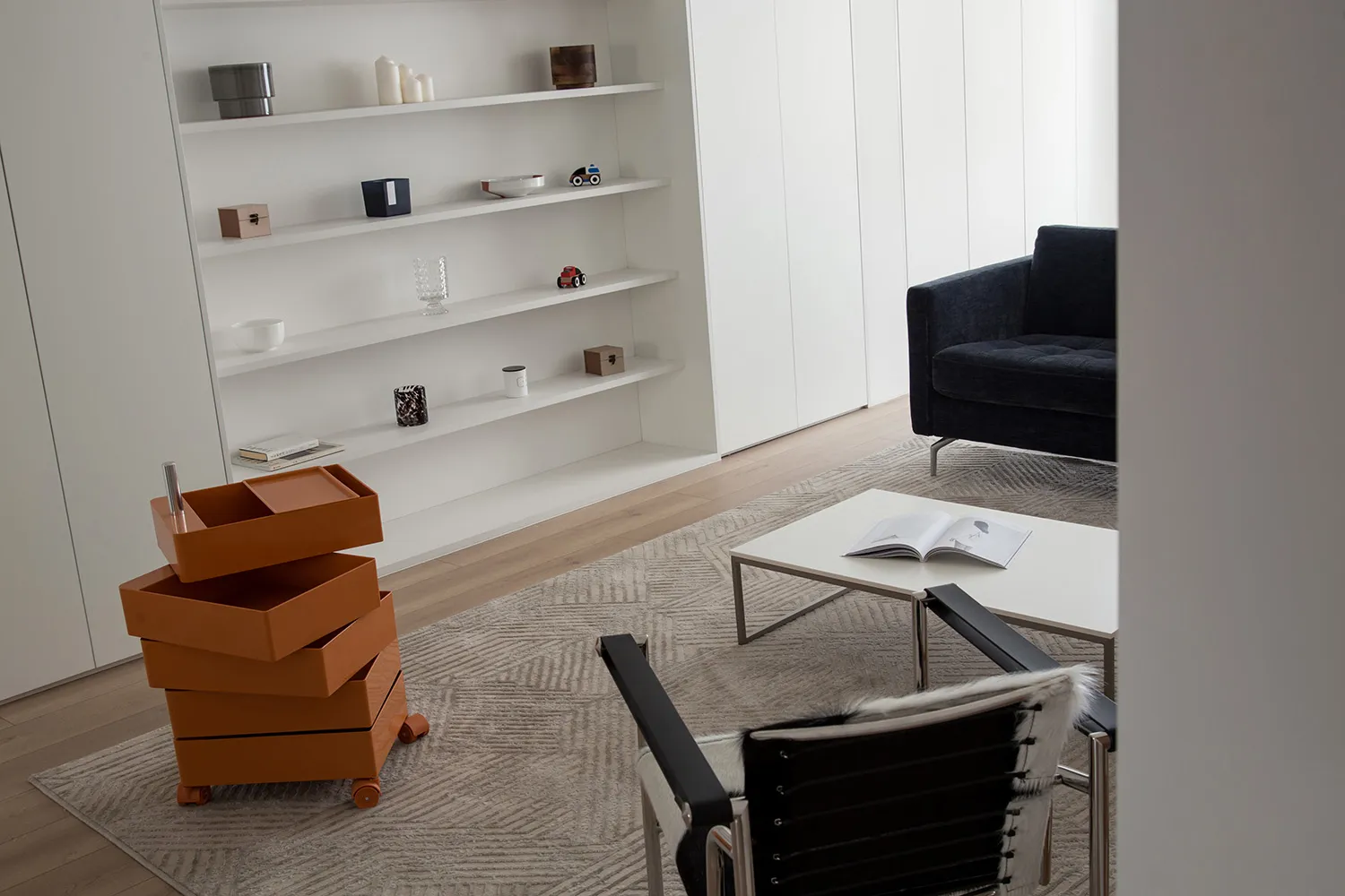 A modern minimalist living room with white furniture and a clean, organized space.