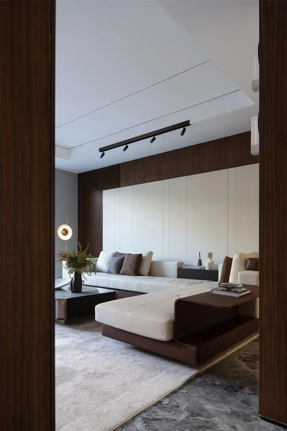 Modern, minimalist living room featuring a white sofa, black coffee table, and white and brown decorative elements, all set a