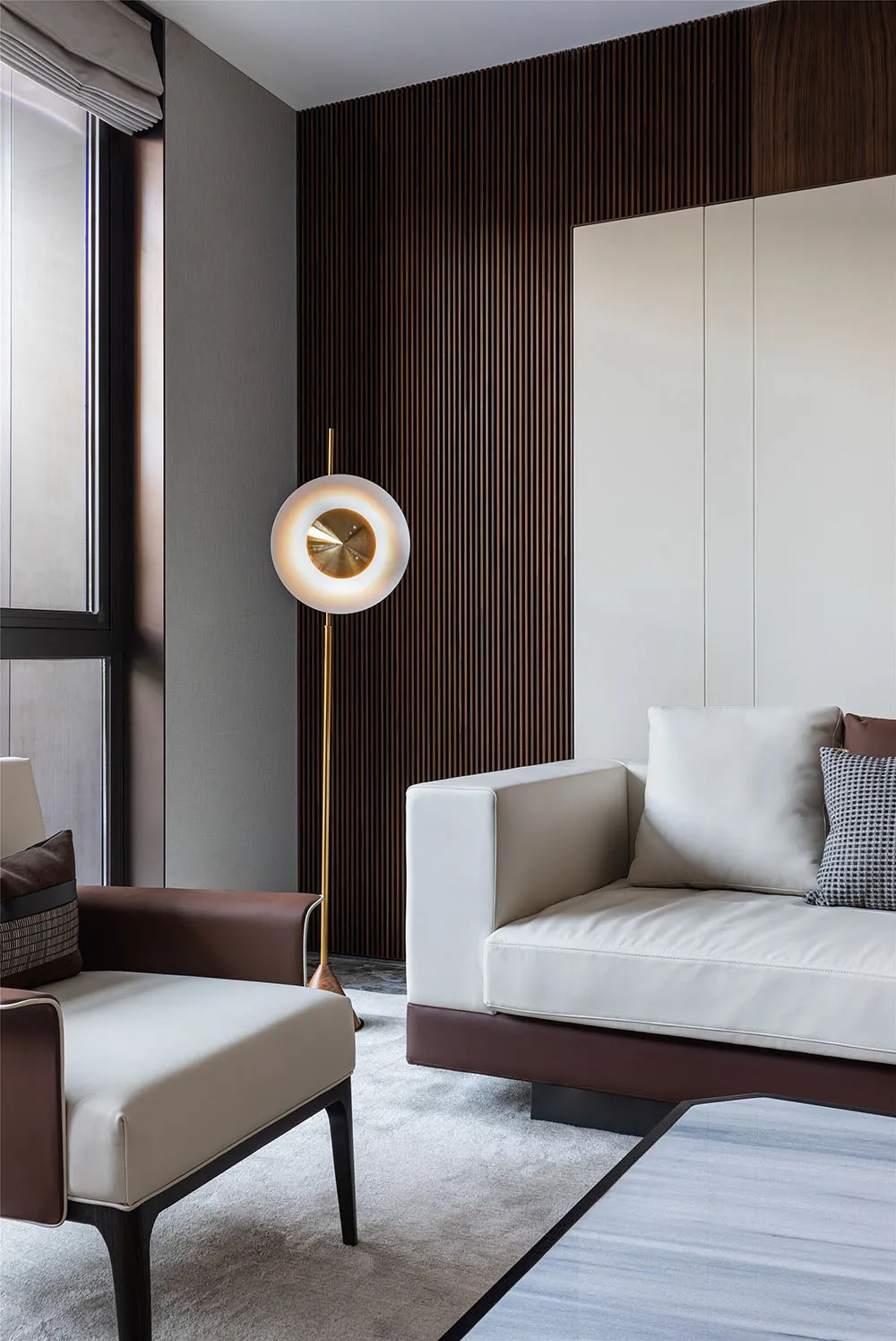 A modern living room featuring wood-paneled walls, white sofas with brown accents, and sleek, minimalist furnishings.
