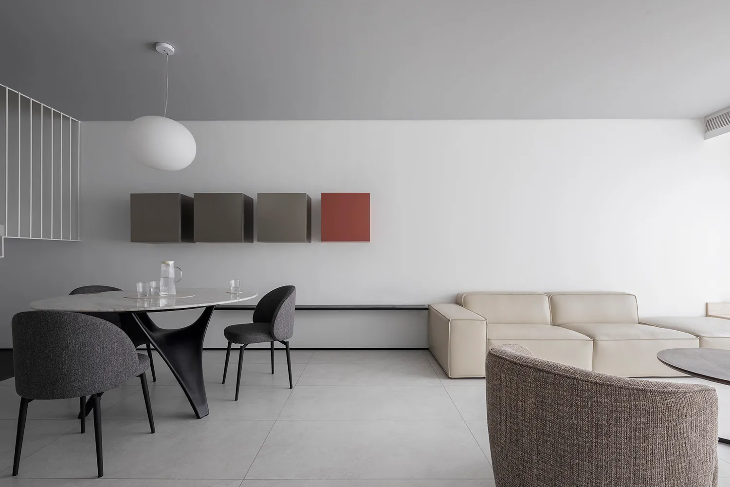 A modern living room with a minimalist design, neutral-colored furniture, and a white and black sofa.