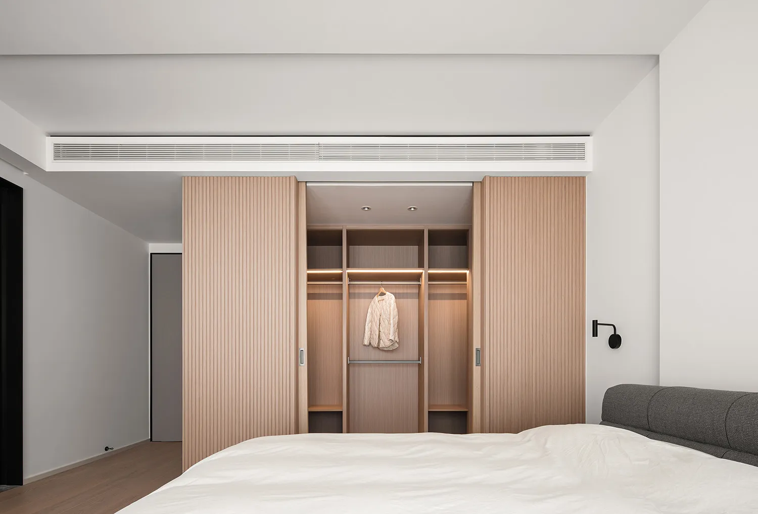 Modern minimalistic bedroom featuring wooden closet and bed.