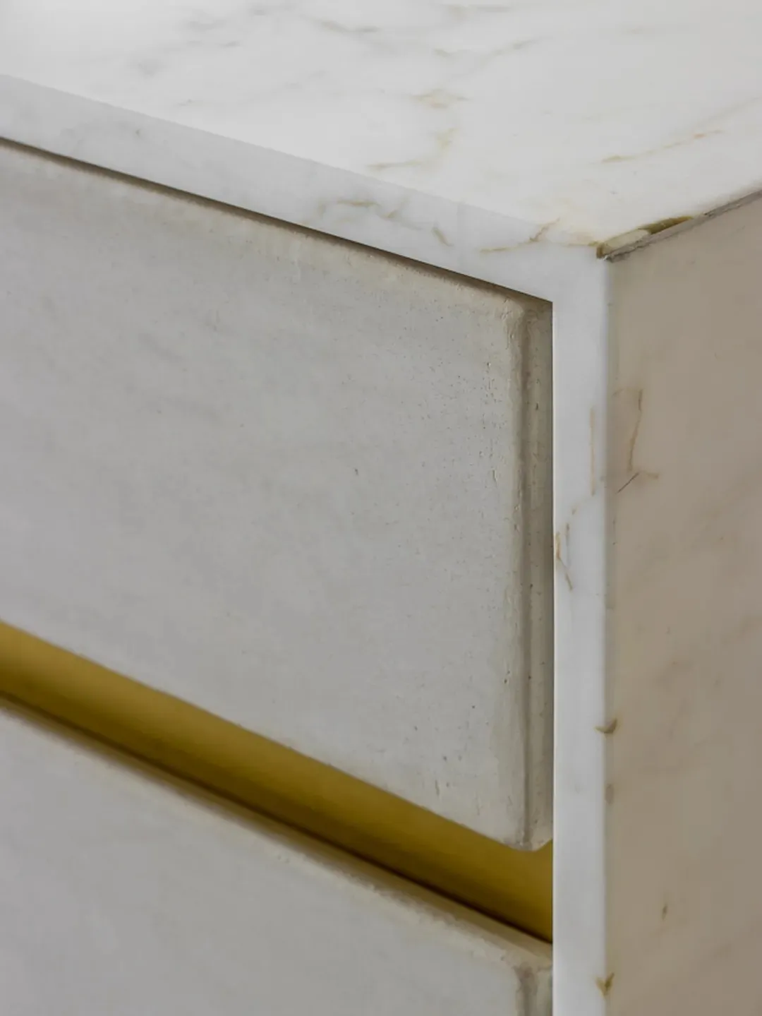 A sleek, modern side table made of white marble with gold accents.