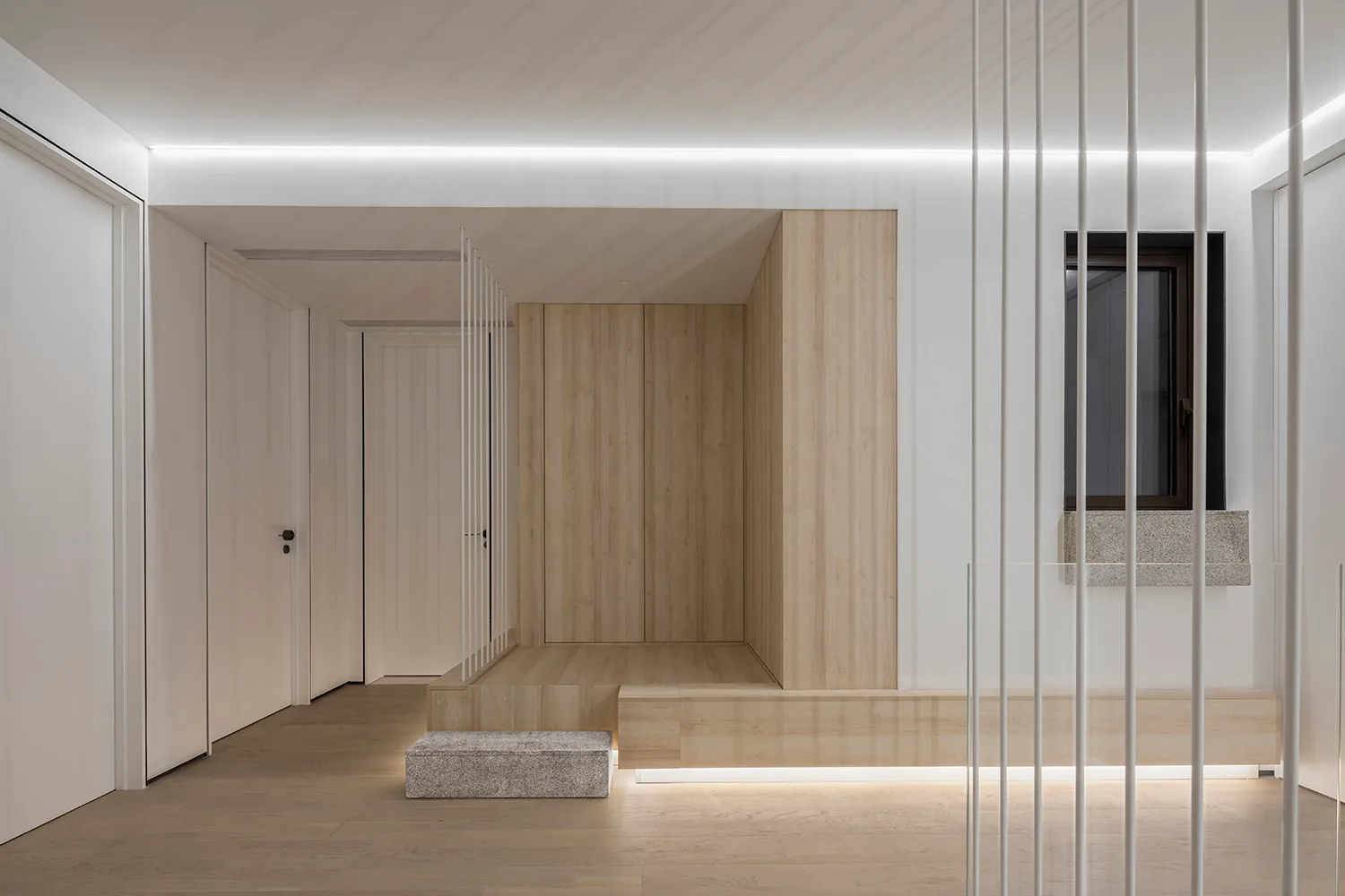 A minimalist residential entryway featuring wooden paneling and a large window.
