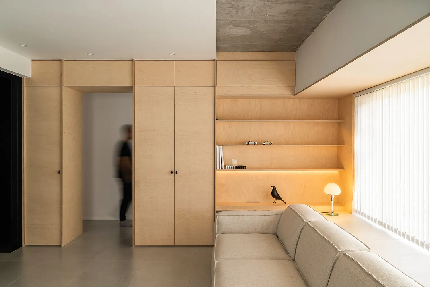 A minimalist living room featuring wood storage units and a beige sofa.