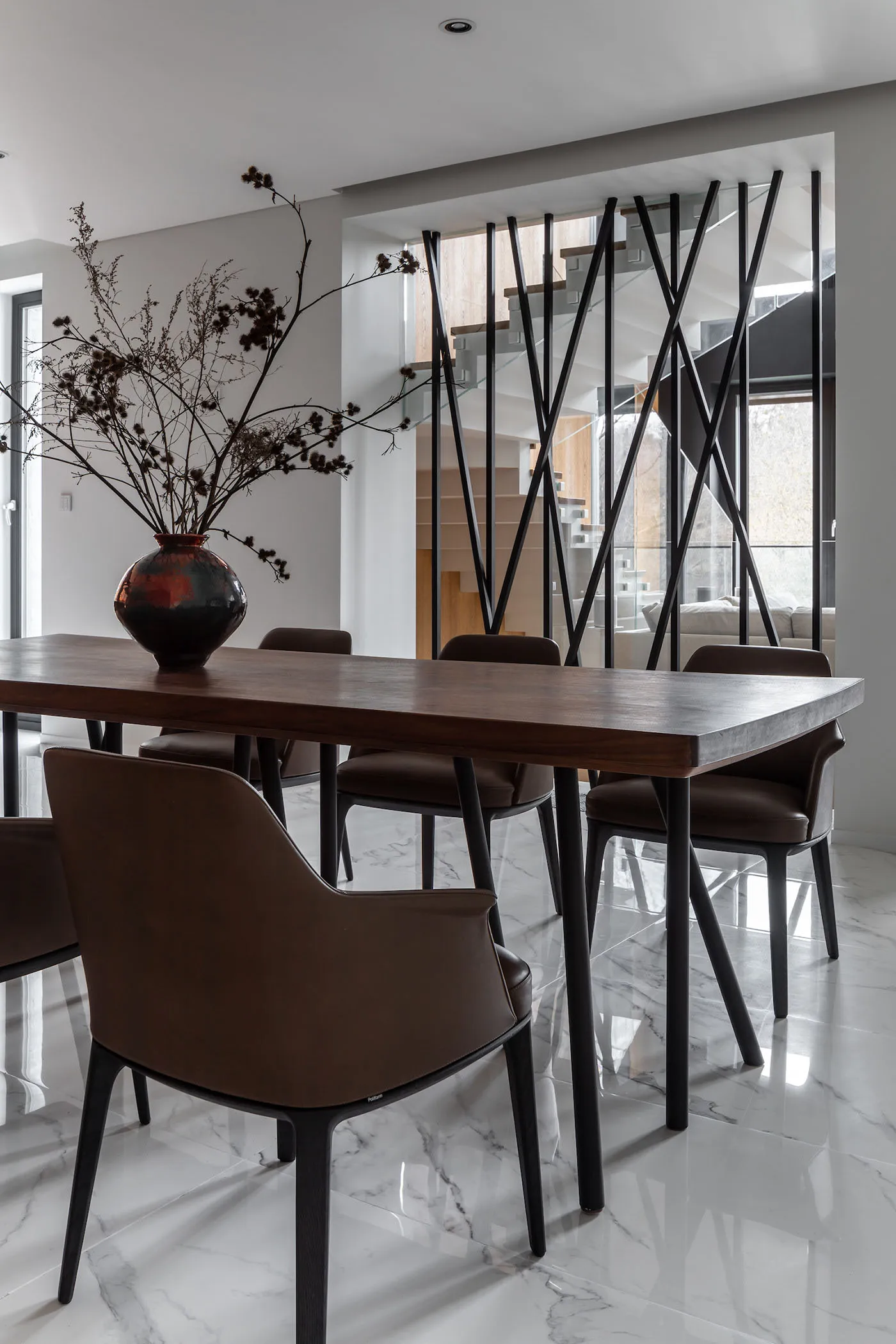 A modern dining room with wooden table, leather chairs, glass vase, and minimalist design.
