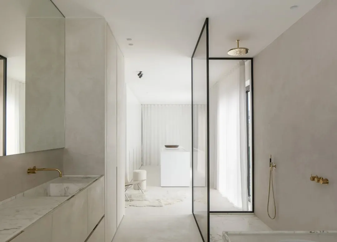 A modern minimalist bathroom with concrete walls and floor, featuring a glass-enclosed shower and a floating vanity with a ma