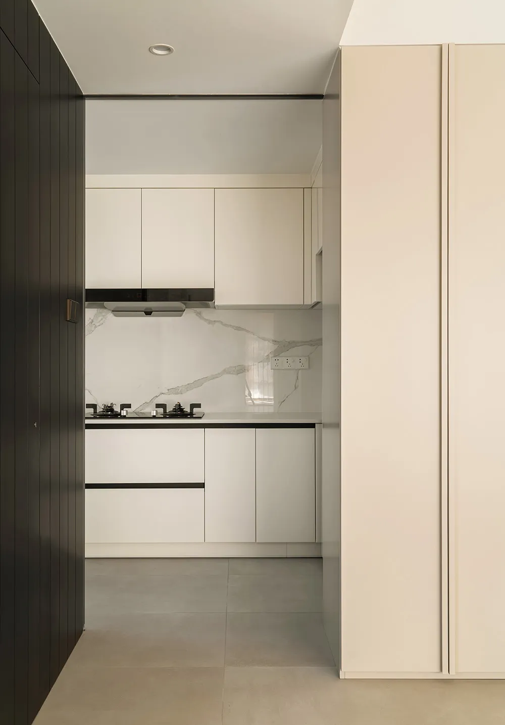 A modern minimalist kitchen with a white marble countertop and white cabinets.