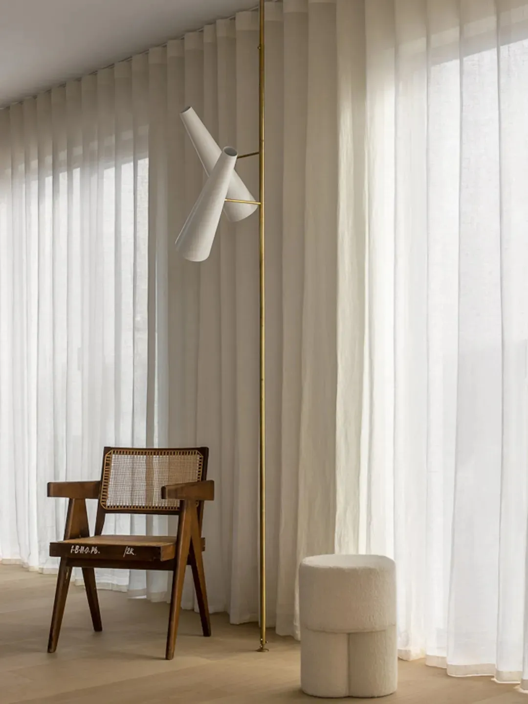 Minimalist living room with white curtains, wooden chair, and white floor lamp