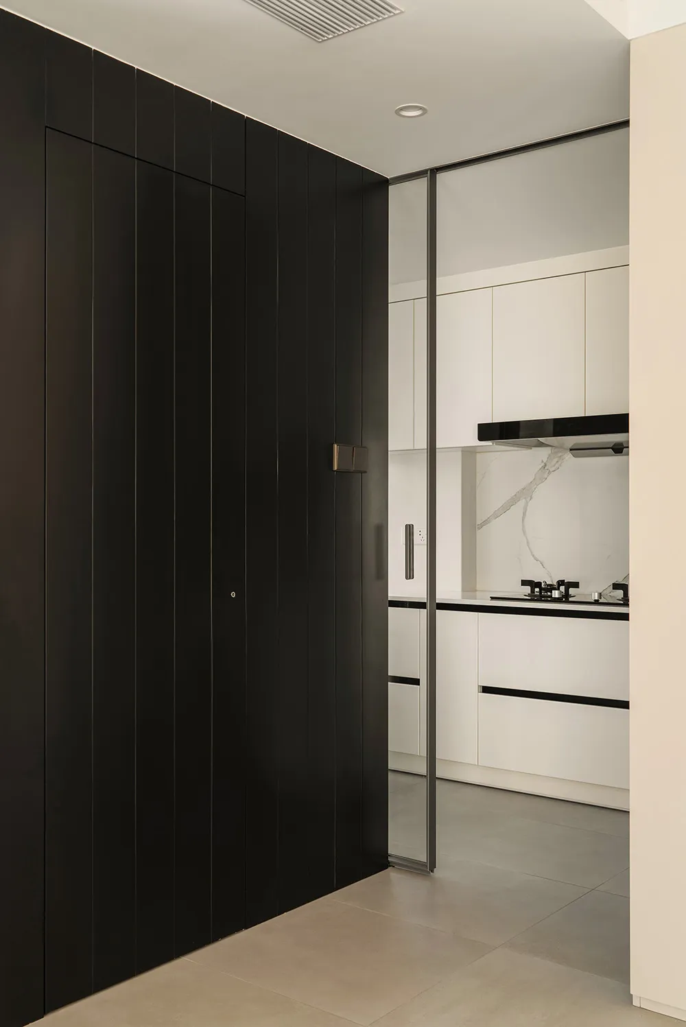 Modern minimalist kitchen featuring glossy white marble countertops and white cabinets with black accents.