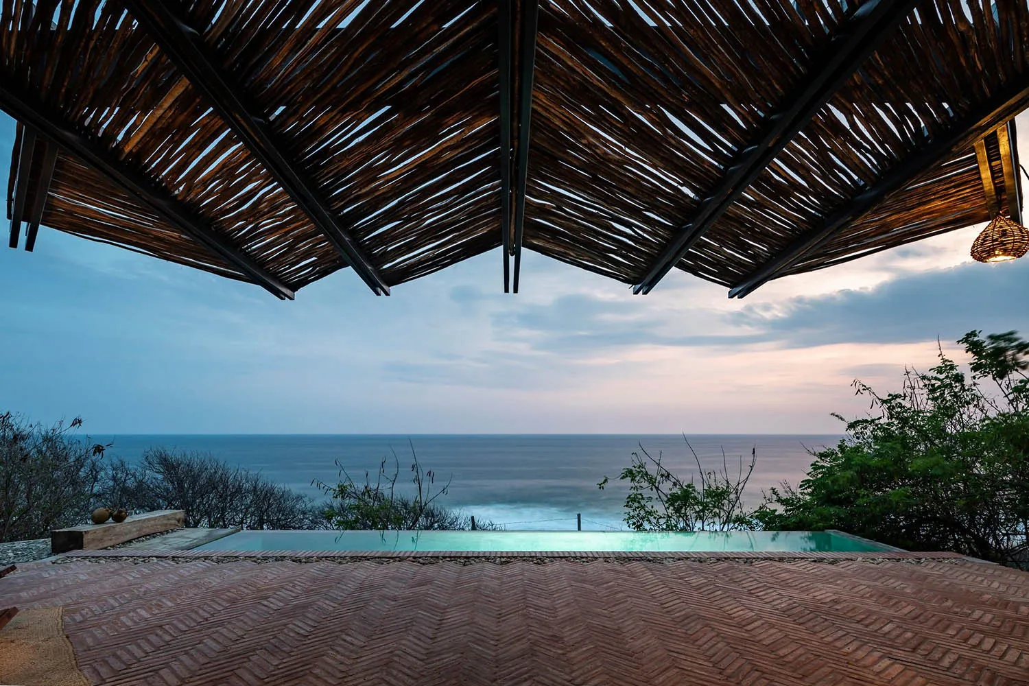 A wooden roof with a view of the ocean and tropical surroundings.