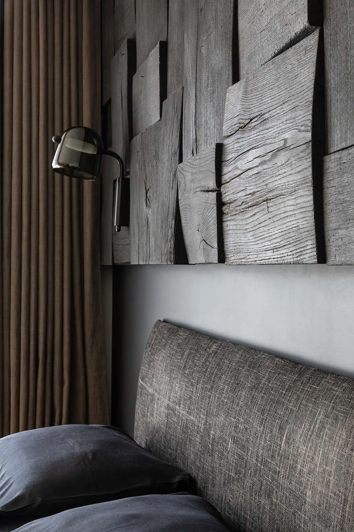 Modern bedroom with grey fabric headboard and wood paneling on the wall