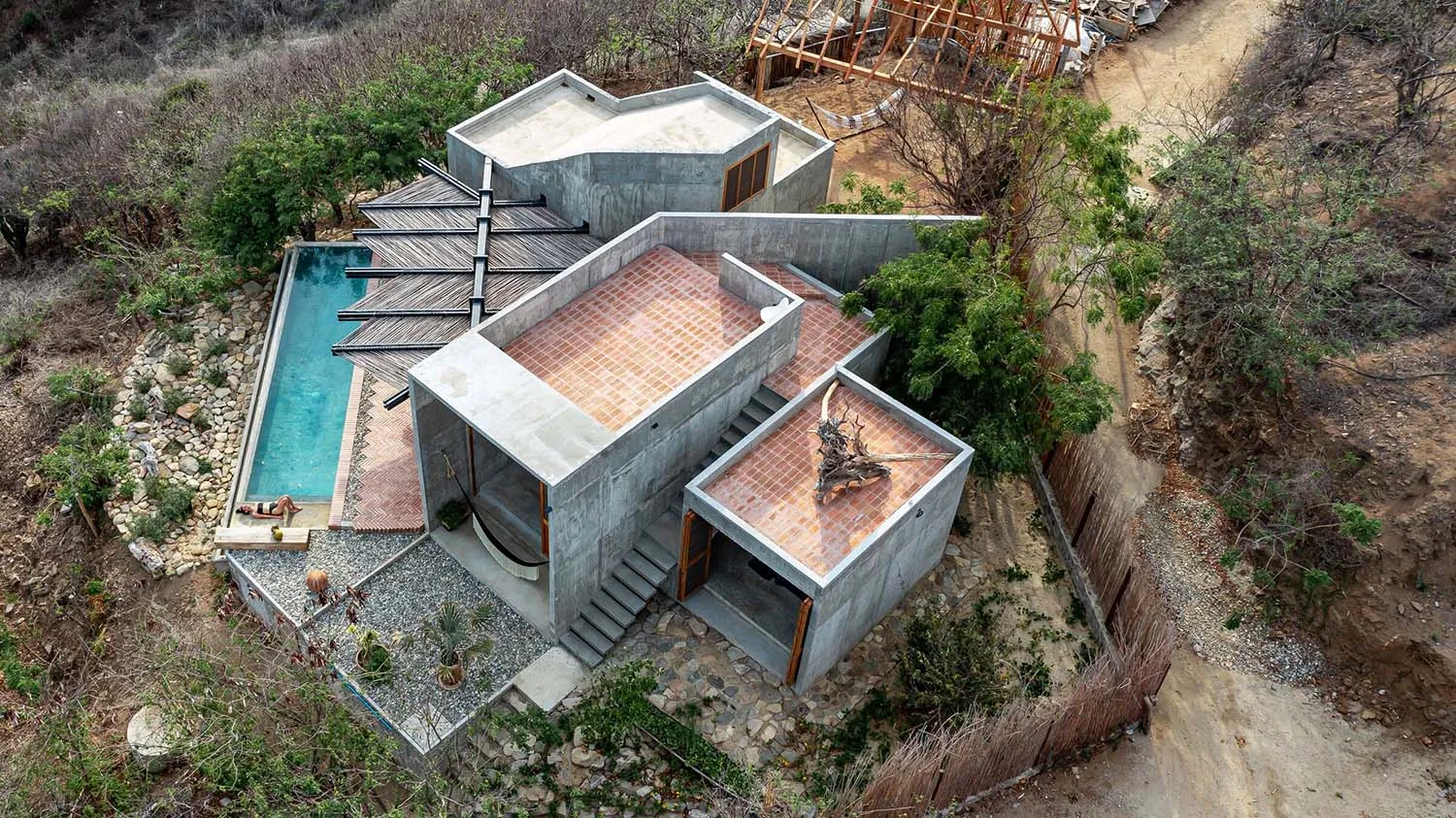 A modern concrete house with a pool and terracotta tiled rooftop.