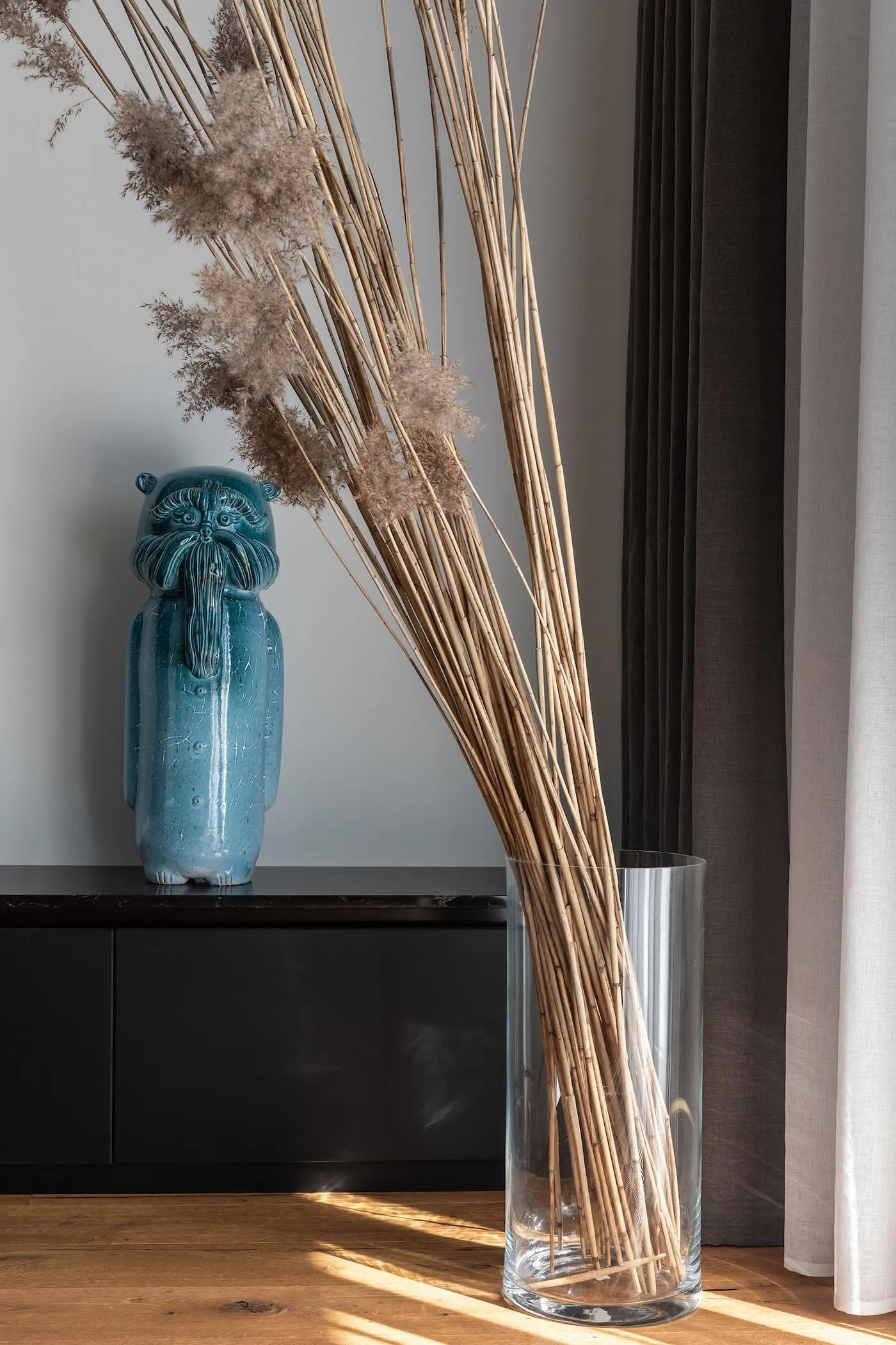 A decorative vase filled with dried plants, placed on a table in a room setting.