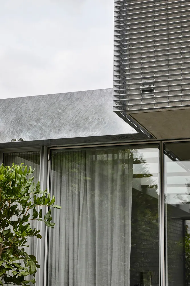Modern exterior of a house with stone cladding and large glass windows.
