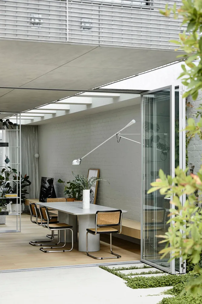 Modern minimalist dining room featuring sleek, contemporary furniture with a concrete table and wooden chairs.