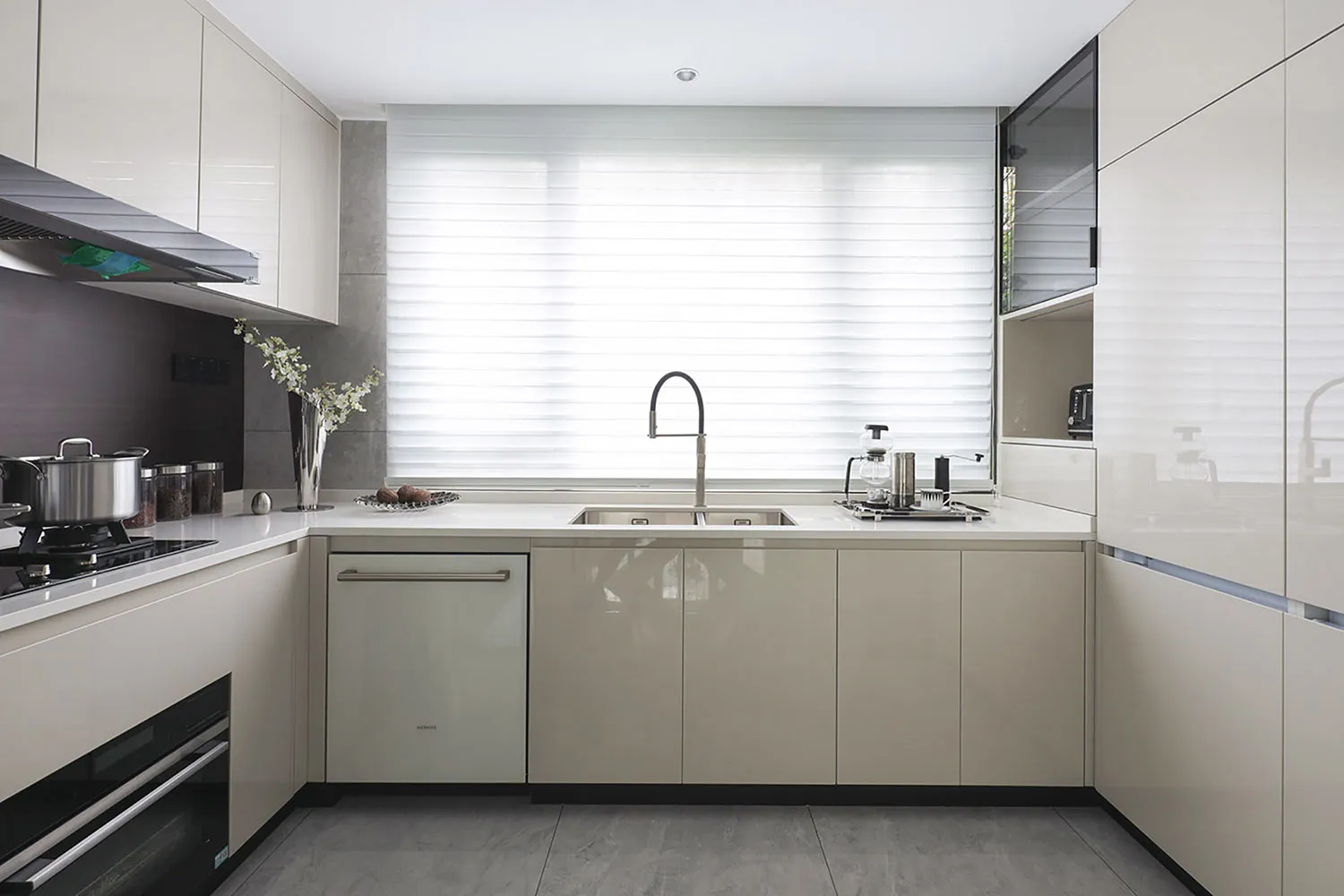 Modern minimalist kitchen with ceramic countertops, white cabinets, and stainless steel appliances.