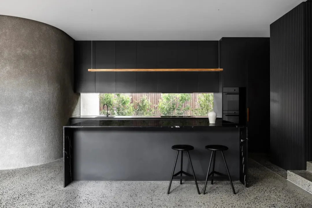 A modern kitchen featuring black marble countertops and sleek black cabinetry.