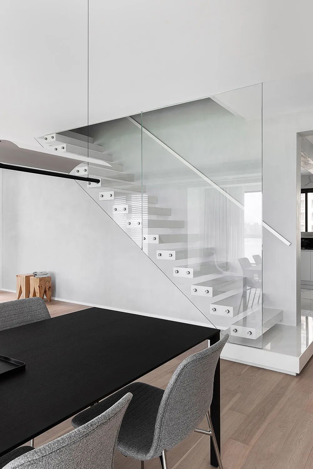 Modern dining room featuring a glass and metal staircase