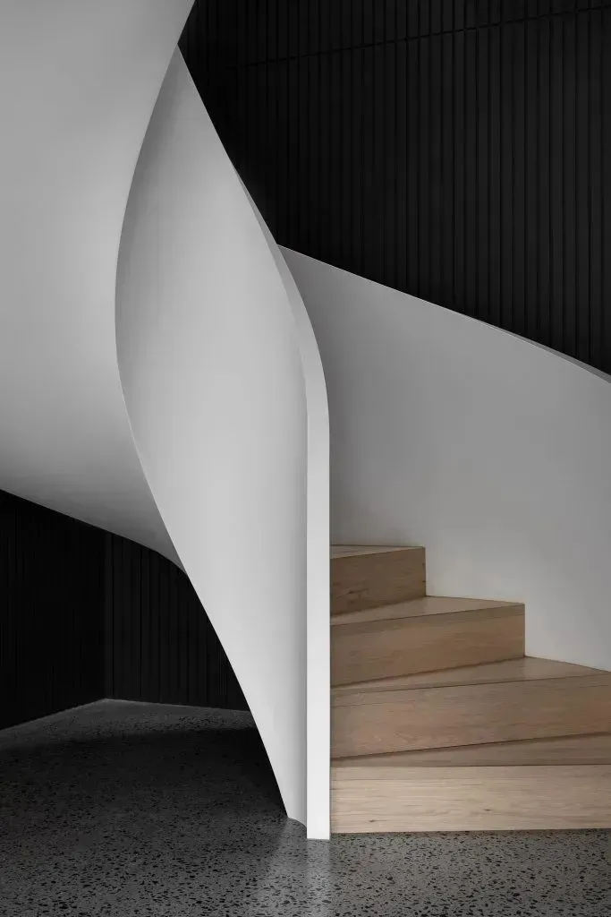 Modern industrial interior with concrete walls and a wooden staircase.