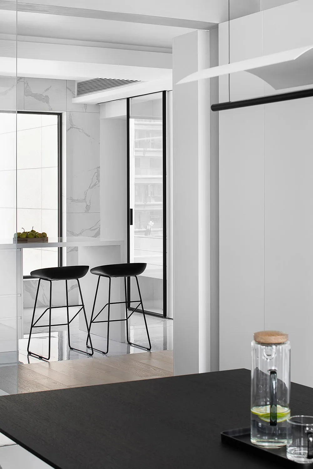 A modern kitchen and dining area with black stools and marble surfaces.
