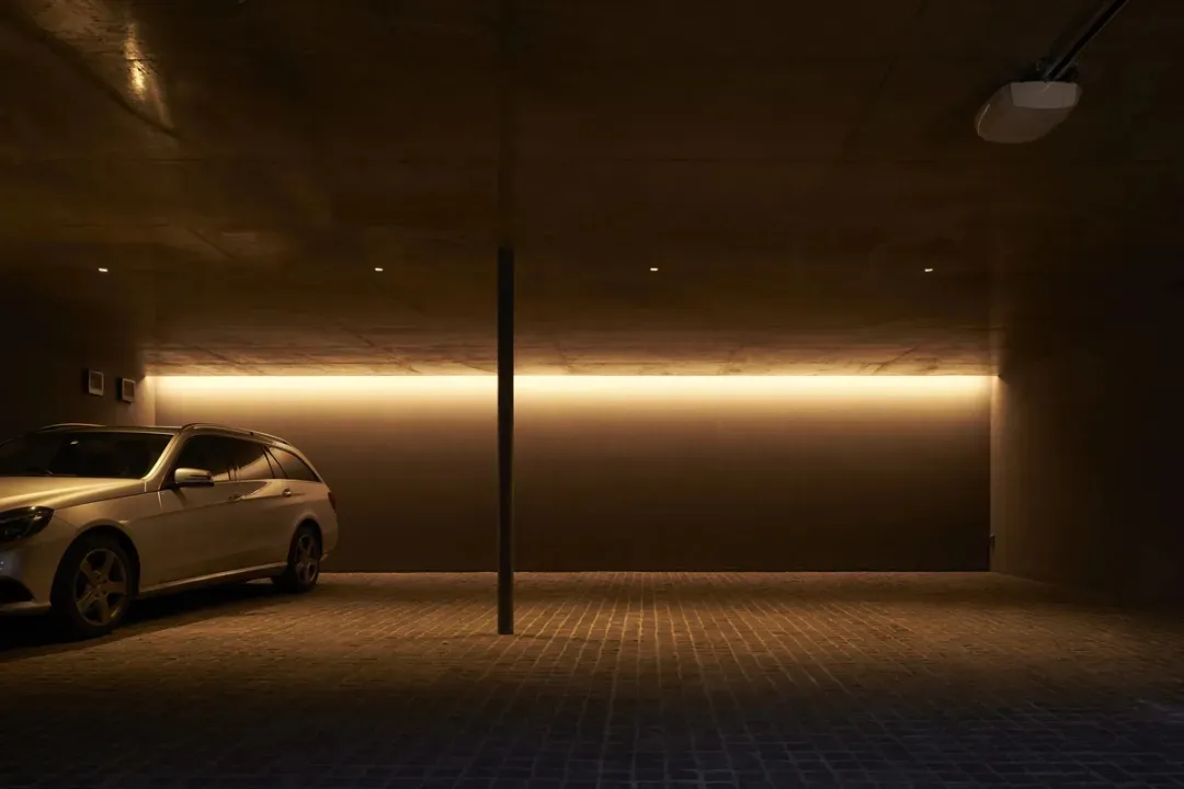 Modern minimalist garage with concrete walls, brick flooring, and recessed lighting