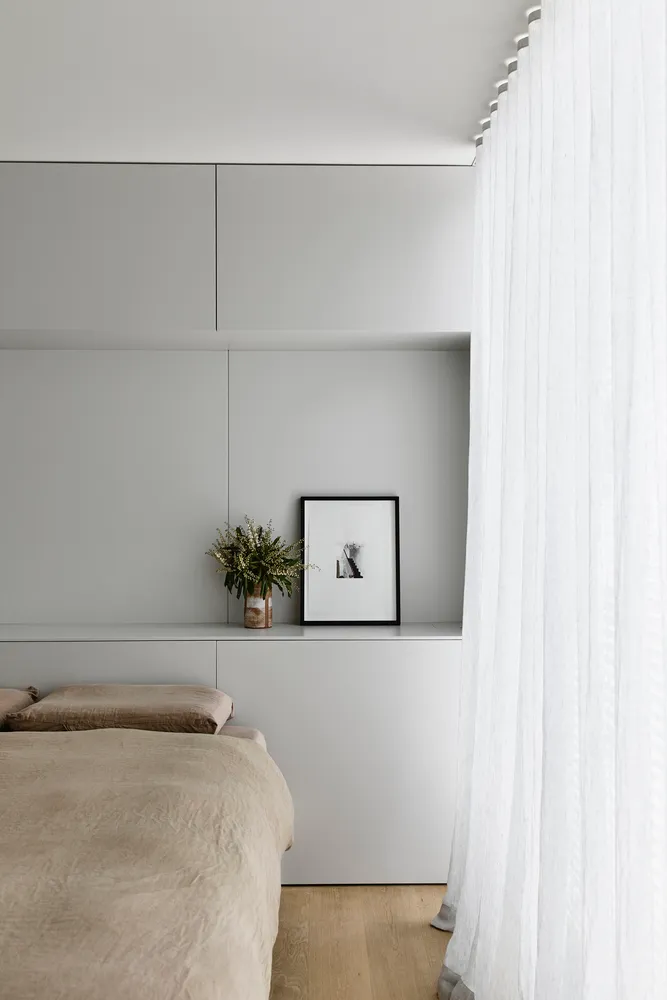 A minimalist bedroom with neutral-toned bedding and a modern, sleek design.