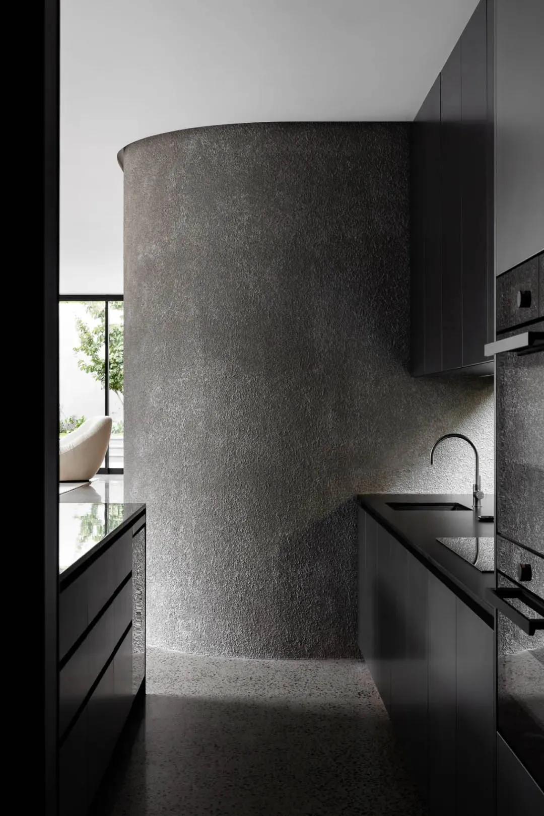 Modern minimalist kitchen featuring gray concrete walls and black cabinetry.