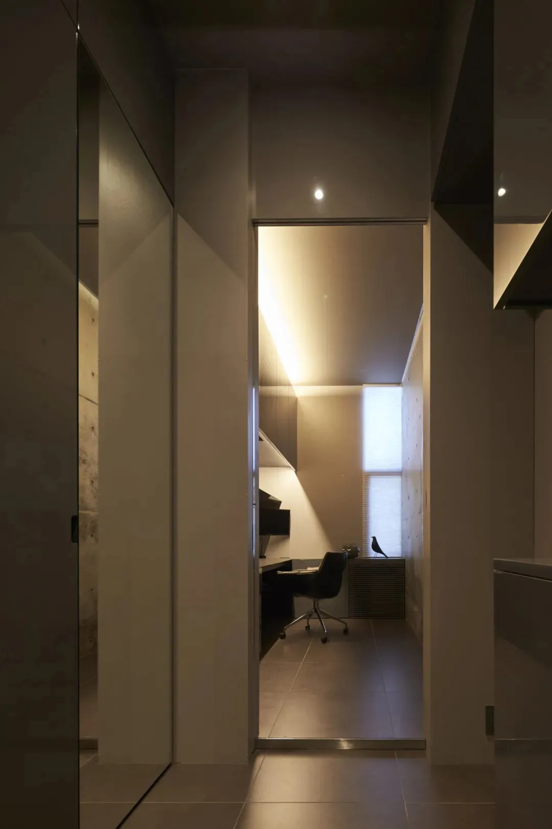A modern office hallway with concrete walls and a central light source.