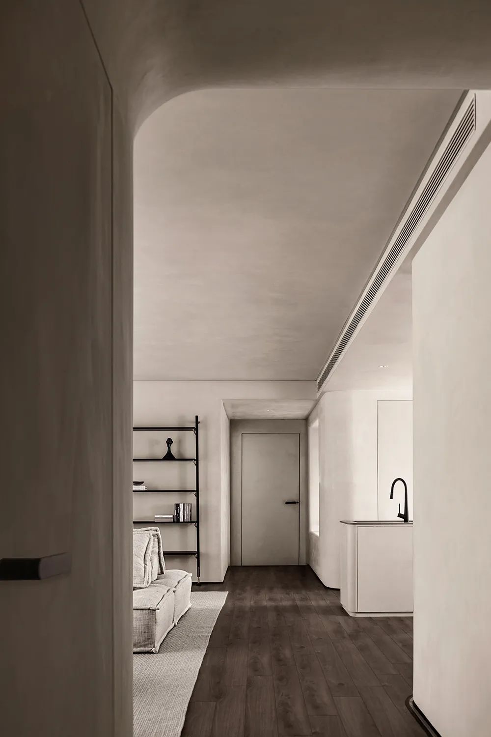 Modern minimalist kitchen with concrete finishes and dark wood flooring.