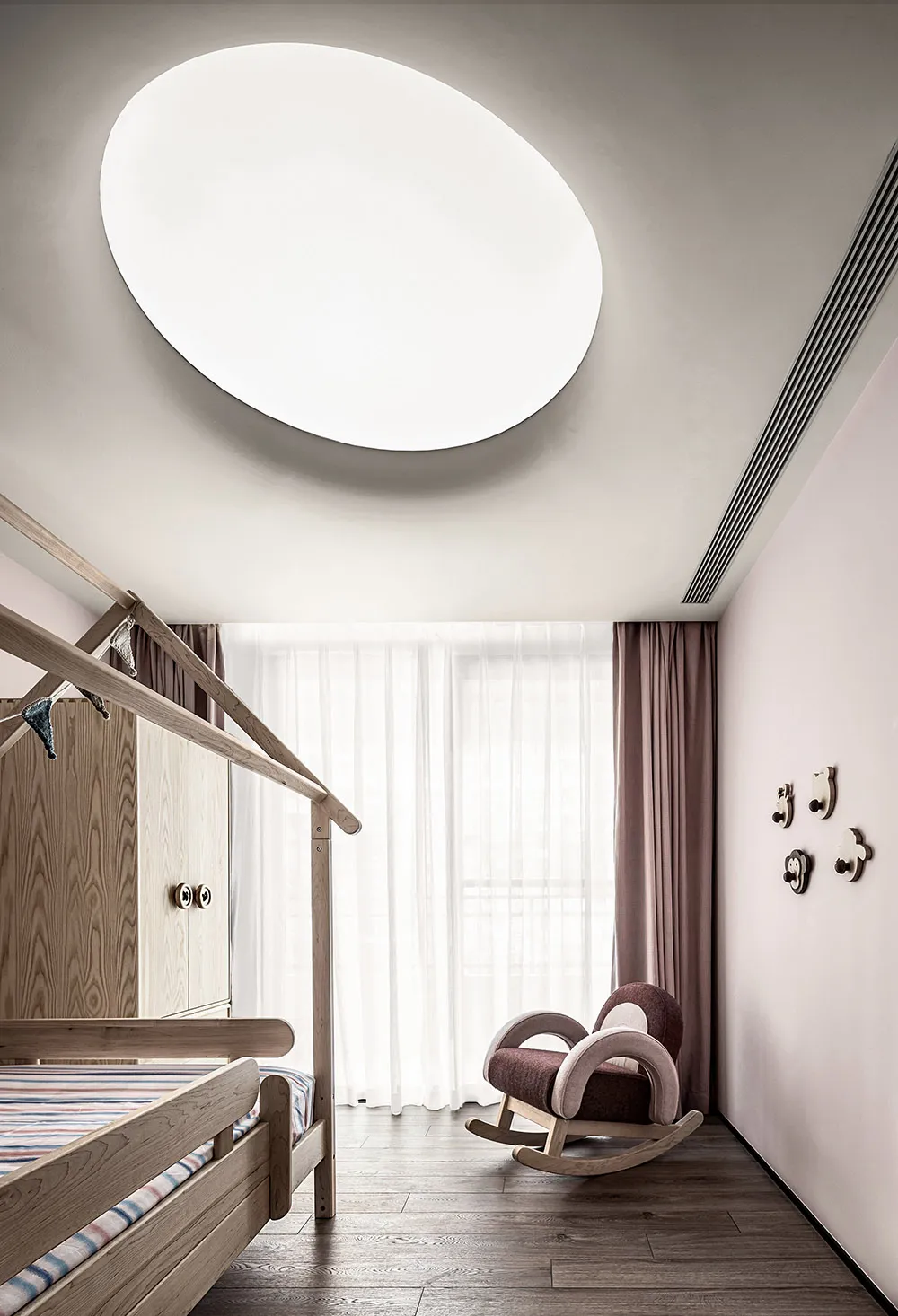Modern minimalist bedroom featuring a wooden frame bed with a large oval cut-out in the ceiling, pink curtains, and a rocking