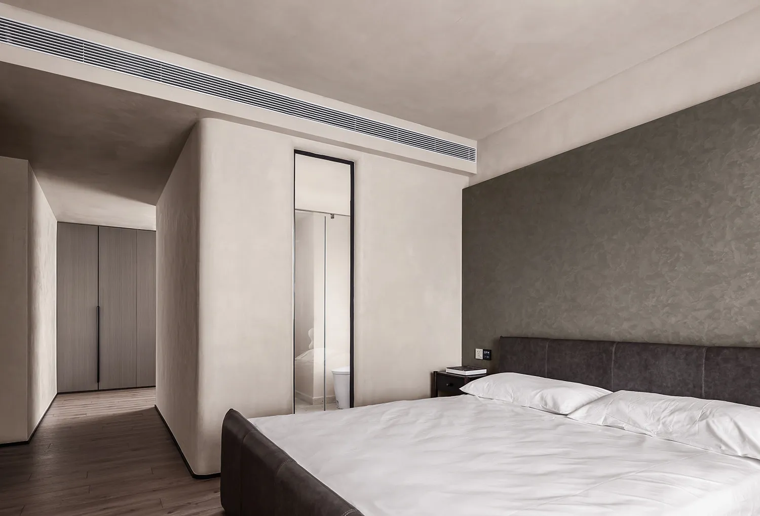Minimalist bedroom with textured walls and white bedding.